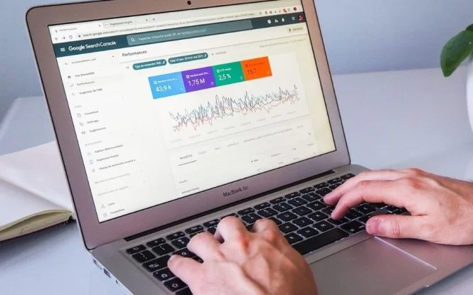 Hands typing on a MacBook Air displaying digital marketing performance data in Google Search Console.