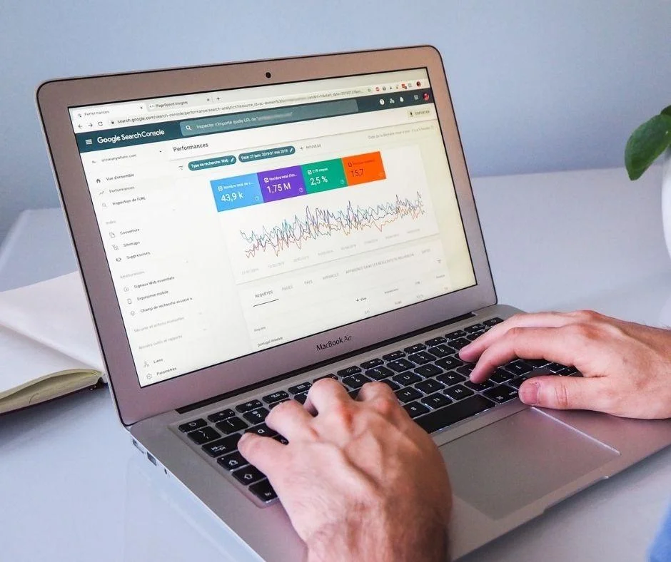 Hands typing on a MacBook Air displaying digital marketing performance data in Google Search Console.