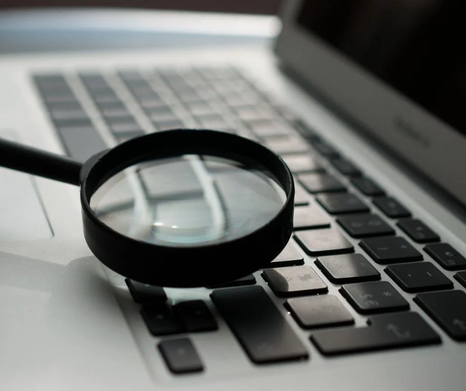 A magnifying glass resting on a laptop keyboard, symbolizing close analysis of digital marketing performance.