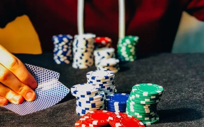 Poker player holding cards beside chip stacks, symbolizing strategic risk in managing a paid media budget.