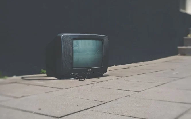 An old discarded television abandoned on a sidewalk, symbolizing shifting ad spend away from traditional TV media.