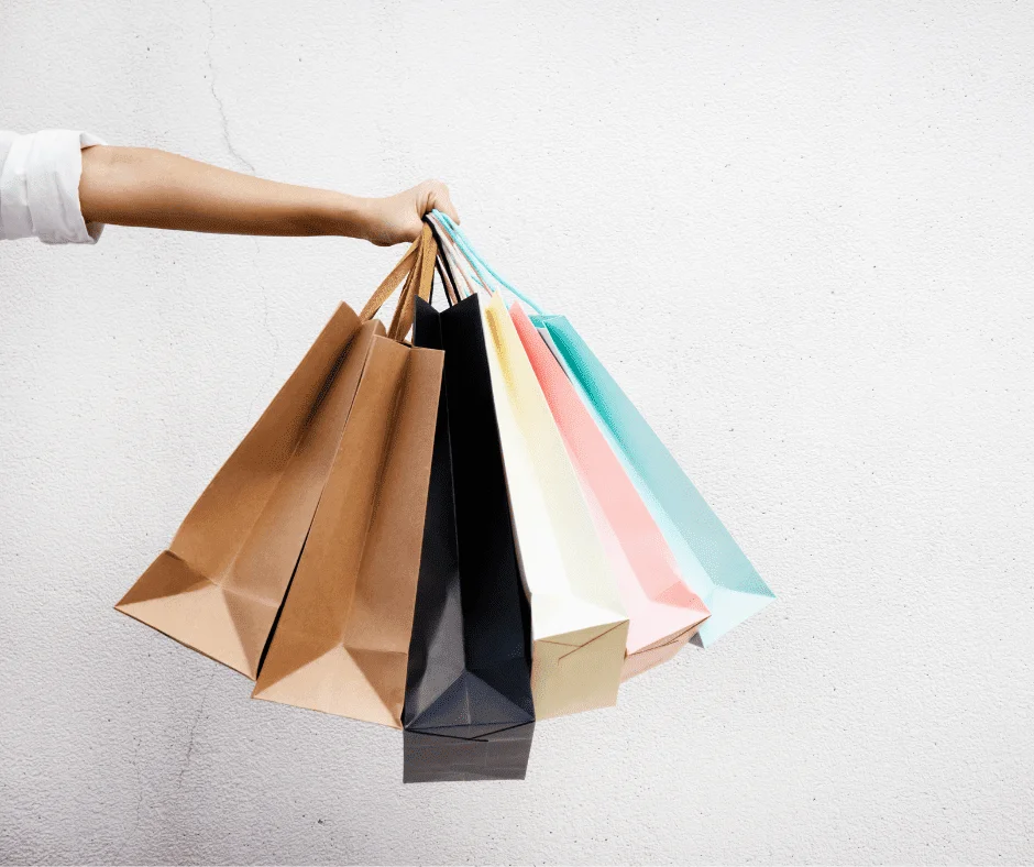 Arm holding multiple colorful shopping bags, symbolizing retail trends shaping the Future of Commerce.