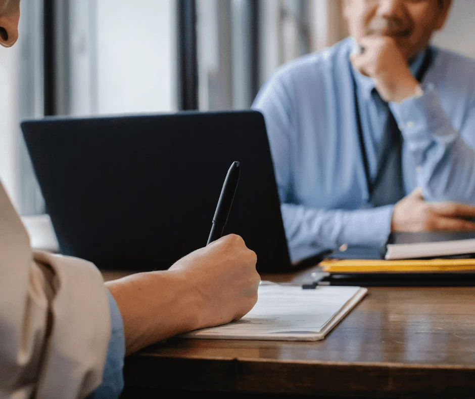 Person taking notes during a meeting, illustrating how to impress your CMO with confident ad performance forecasting.