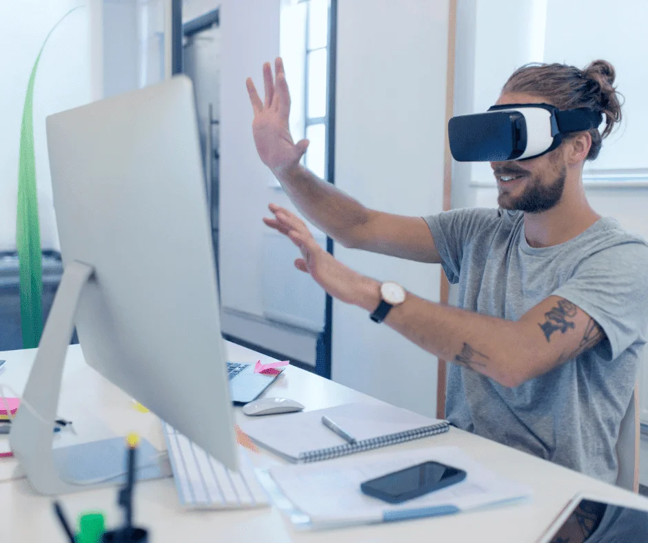 Man wearing a VR headset at his desk, gesturing with hands, illustrating emerging digital marketing trends.