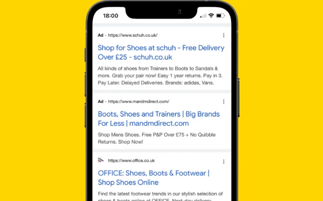 Smartphone displaying Google search results with Extended Text Ads for shoe retailers like schuh and OFFICE.