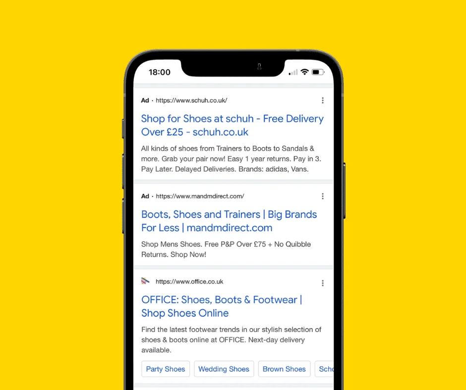 Smartphone displaying Google search results with Extended Text Ads for shoe retailers like schuh and OFFICE.