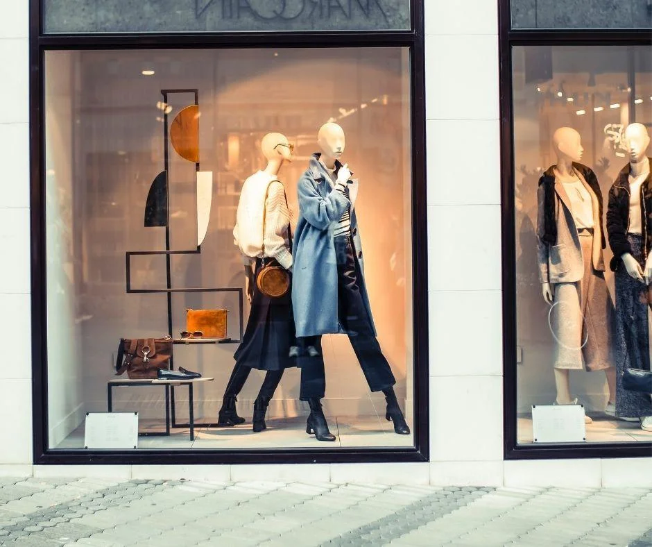 Fashion store window display with mannequins in coats, reflecting UK retail trends amid Boohoo's expansion.