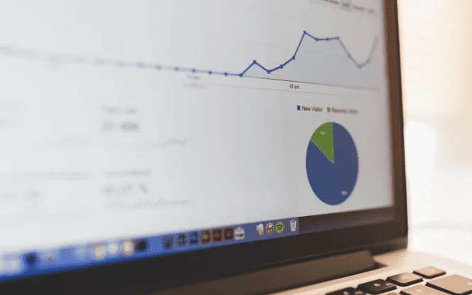 Laptop screen displaying GA4 attribution analytics dashboard with visitor trend graph and pie chart