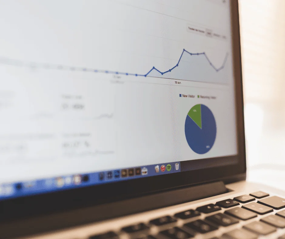 Laptop screen displaying GA4 attribution analytics dashboard with visitor trend graph and pie chart