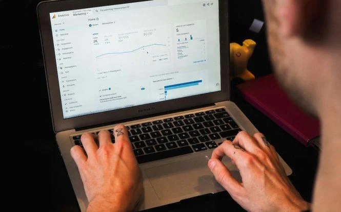 Person analyzing a GA4 analytics dashboard on a laptop, exploring GA4 pros and cons for marketing insights.