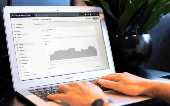 Hands typing on a MacBook Air displaying Google Search Console coverage report, illustrating set-up-google-search-console steps.