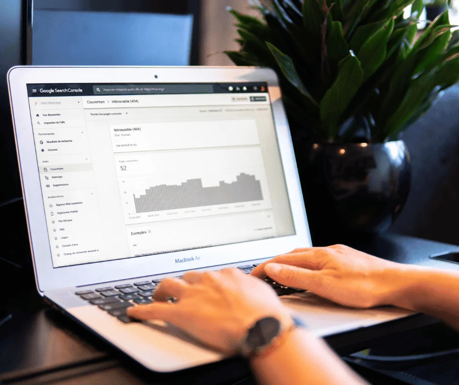 Hands typing on a MacBook Air displaying Google Search Console coverage report, illustrating set-up-google-search-console steps.