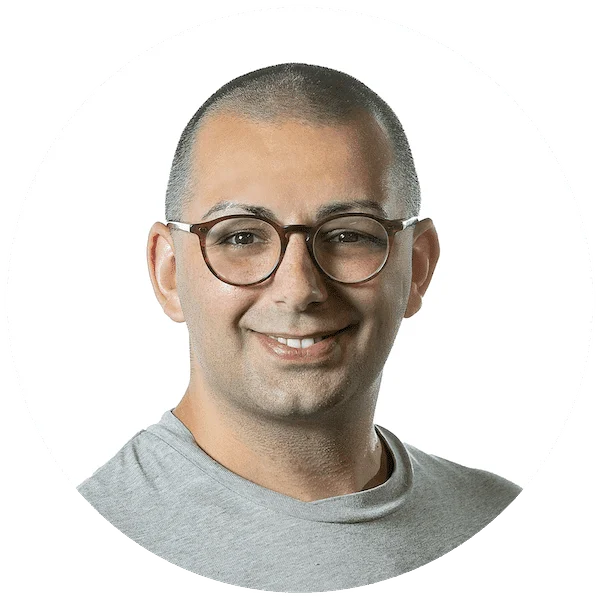Smiling man with glasses and a shaved head, wearing a gray t-shirt, in a profile picture.