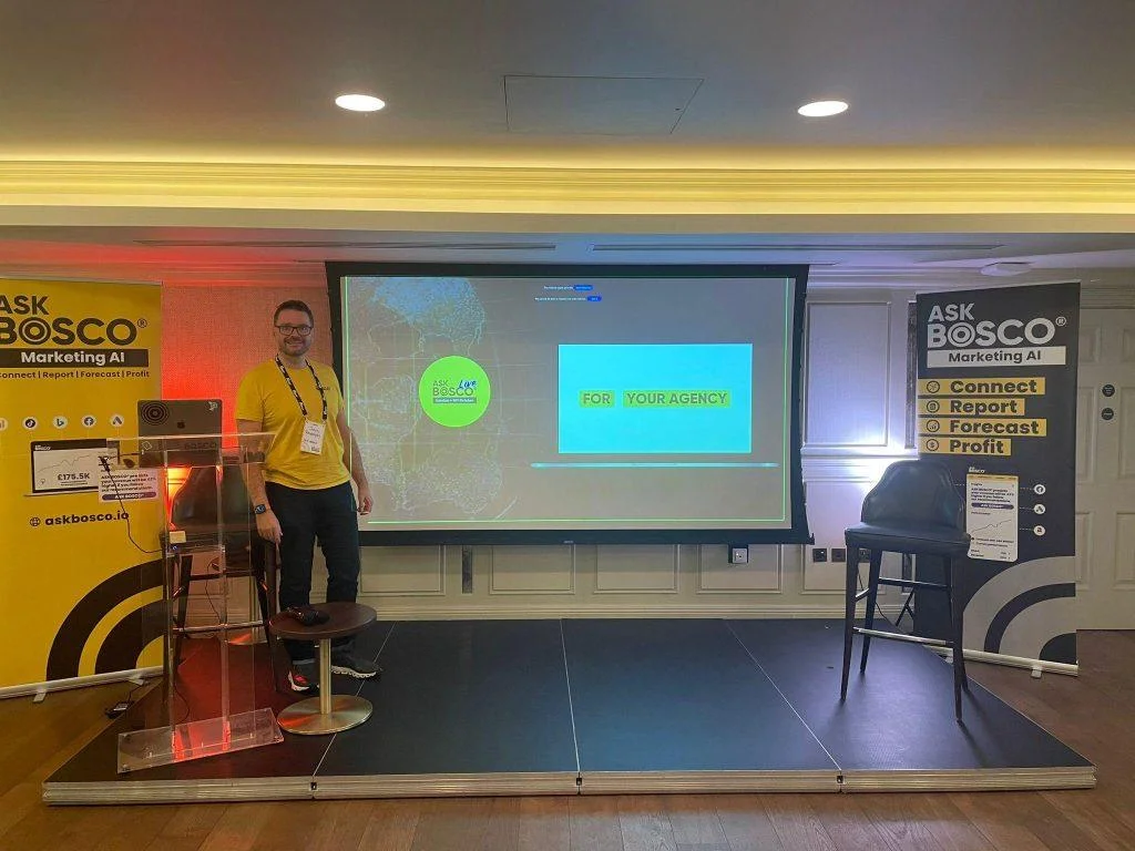 Speaker presenting at ASK BOSCO® Live 2023 beside a screen reading "For Your Agency" on stage