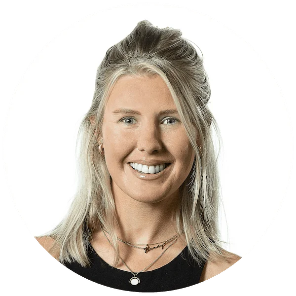 Professional headshot of a smiling woman with blonde hair, wearing layered necklaces and a black top.