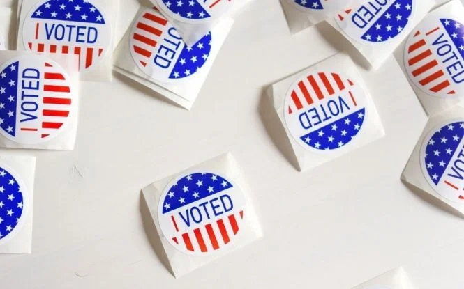 Scattered "I Voted" stickers with American flag design, symbolizing participation in the US election.