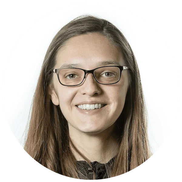 Professional headshot of a smiling woman with long brown hair wearing glasses, in a circular profile photo.