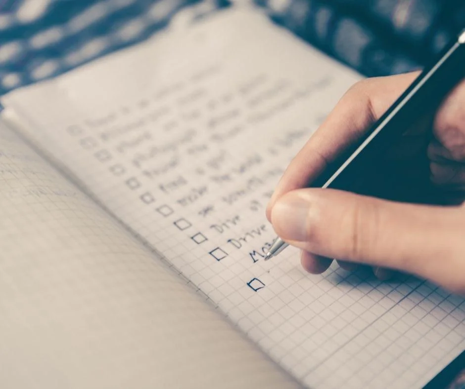 Hand writing on an SEO checklist with checkboxes on graph paper using a pen