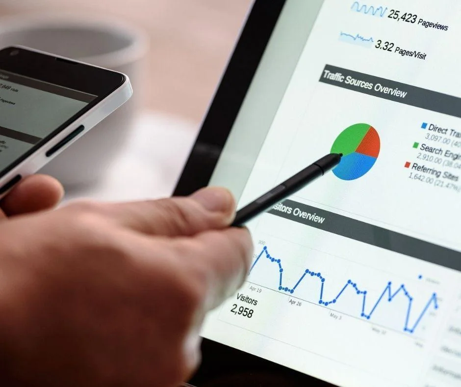 Hand holding a stylus over a tablet displaying website traffic analytics, useful for evaluating PPC ad performance.